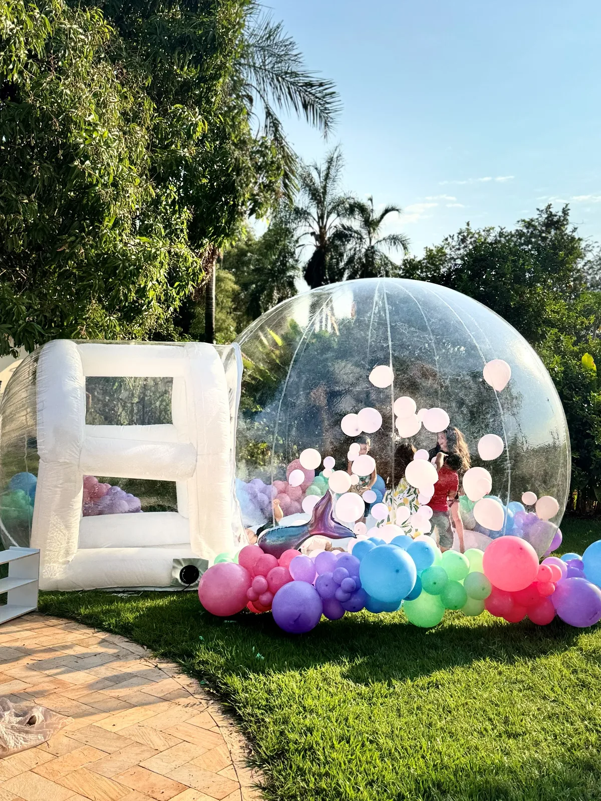 Bubble Dream House montada no jardim com arco de balões coloridos ao fim da tarde